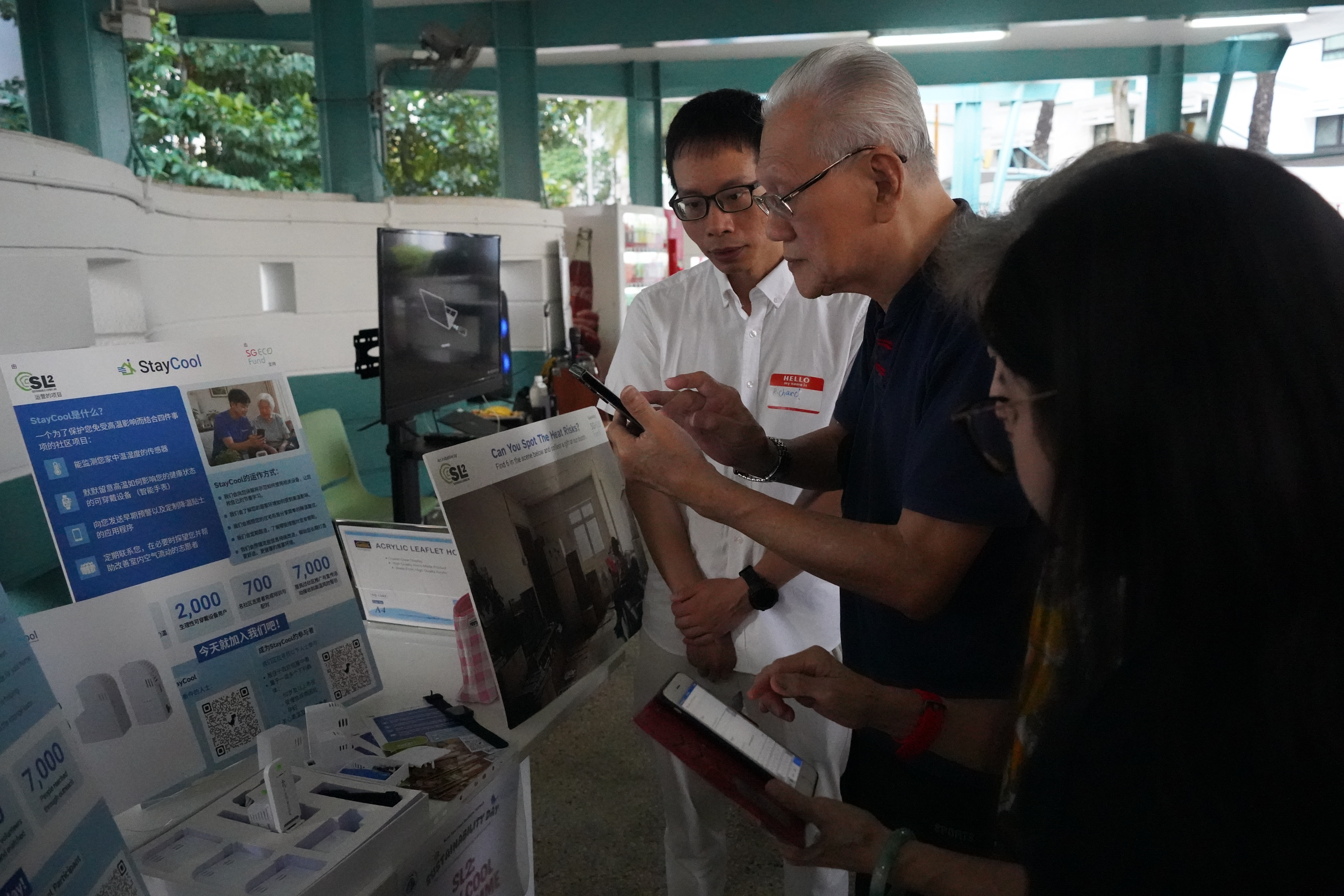 A StayCool volunteer explaining the StayCool programme and heat safety tips to a senior at a community outreach event.